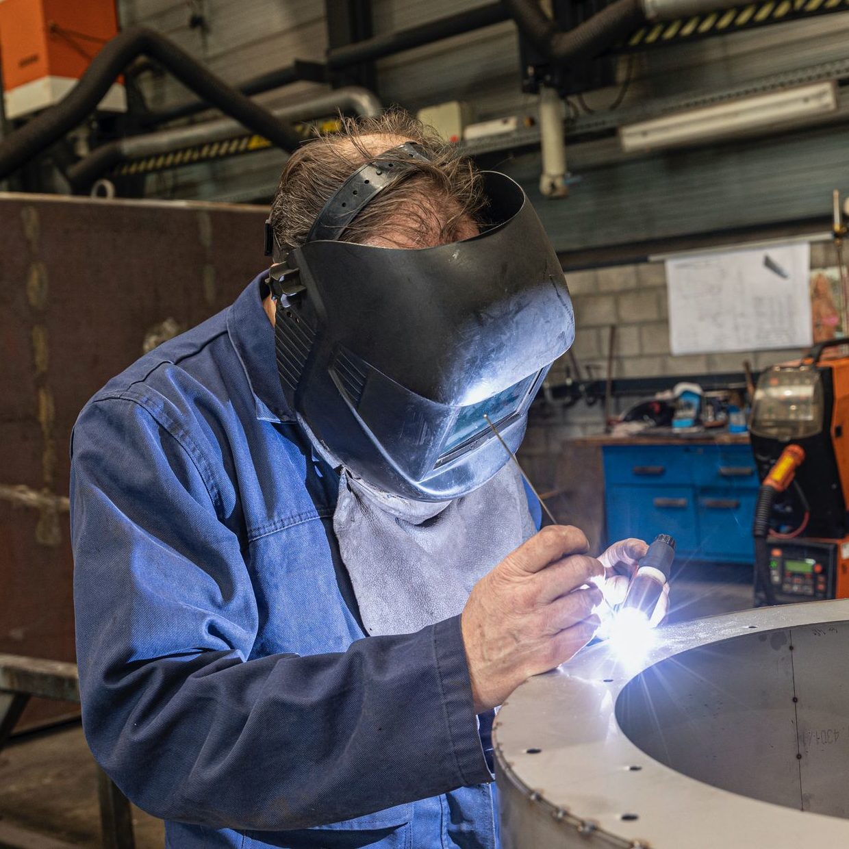 A skilled welder working in a modern workshop with advanced equipment and safety gear.